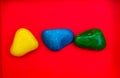 Multi color Natural Pebbles Green, Blue and yellow stone isolated on red background with space for copy text and words. Colorful