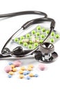 Multi color pills spills around the stethoscope