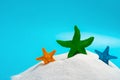 Multi color starfishes on white sand on blue concept of summer vacations