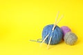 Multi-colored balls of yarn with knitting needles on yellow background Royalty Free Stock Photo