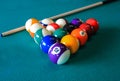 Multi colored billiard balls in the form of a triangle with numbers and cue ball on a pool table. Royalty Free Stock Photo