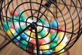 Multi-colored bingo balls in cage sitting on a desk.