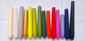 Multi-colored burnt candles stand in a row on a white background. Royalty Free Stock Photo