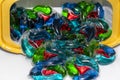 Multi-colored capsules for washing clothes rashing from a plastic container on a white background, close-up, selective focus. Royalty Free Stock Photo