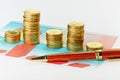 Multi-colored chart and pen with stacks of coins. Royalty Free Stock Photo
