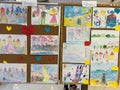 Milan, Italy - 17 august 2023: Multi-colored children drawings hang on a stand
