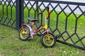 Multi-colored children's bike strapped to the fence