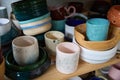 Multi-colored clay cups and bowls are stacked on wooden shelves Royalty Free Stock Photo