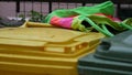 A multi-colored cloth bag lies on colored plastic trash cans. Second hand