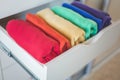 Multi-colored clothes folded vertically in a wardrobe drawer. The concept of order and storage