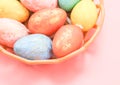 Multi-colored decorative eggs in pastel colors lie in a wicker plastic basket on a light pink. Royalty Free Stock Photo