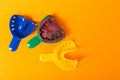 Multi-colored dental spoons for taking an impression of the dental jaw on a orange background. Making an impression of