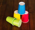 Multi-colored disposable paper, plastic cups on background dark wood. Royalty Free Stock Photo