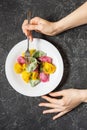 Multi colored dumplings from color dough stuffed with meat on stone background. Female hand holds fork. top view