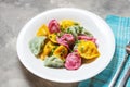 Multi colored dumplings from color dough stuffed with meat on concrete background