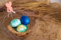 Multi-colored Easter eggs of blue tones and Easter bunny on a stick on a brown cloth background. Close up Royalty Free Stock Photo