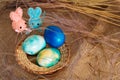 Multi-colored Easter eggs of blue tones and two Easter bunny on a stick on a brown cloth background. Close up Royalty Free Stock Photo