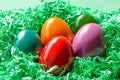 Multi colored Easter eggs, dyed Paschal eggs, in green paper nest