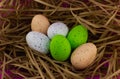 Multi-colored eggs lie in the straw. Easter nest with eggs painted in different colors. On a pink background, a nest Royalty Free Stock Photo