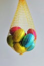 Multi colored eggs wrapped in foil folded into a yellow mesh.