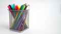 Multi-colored felt-tip pens stand in a mesh transparent glass
