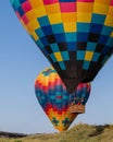 Multi-colored hot air balloons carrying passengers on a clear sunny day in Napa