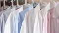 Multi-colored ironed men`s shirts hang on a hanger, selective focus