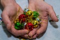 Multi-colored jingle bells in men's hands. Selective focus. On a light background. Close-up Royalty Free Stock Photo