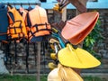 Multi colored kayak paddles on storage rack near the life jackets prepare for hotel or resort guests on holiday summer vacation.