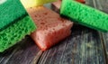 Multi-colored kitchen sponges for washing dishes on a wooden table. Close up Royalty Free Stock Photo