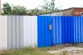 Multi-colored metal fence made of blue, gray and white fences. gate and mailbox Royalty Free Stock Photo