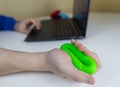 Hand gripper. Man squeezes rubber expander while working on his laptop. Concept of combining useful activity with necessary work. Royalty Free Stock Photo