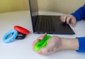 Hand gripper. Man squeezes rubber expander while working on his laptop. Concept of combining useful activity with necessary work. Royalty Free Stock Photo