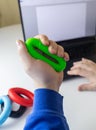 Hand gripper. Man squeezes rubber expander while working on his laptop. Concept of combining useful activity with necessary work. Royalty Free Stock Photo