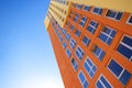 Multi-colored modern residential high-rise building with many glass windows standing against background of blue sky and Royalty Free Stock Photo