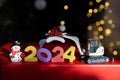 multi-colored numbers 2024, toy mini excavator, souvenir snowman, bokeh