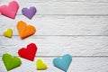 Multi-colored origami paper hearts on a white wooden background.