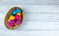 Multi-colored painted Easter eggs in a wicker basket on a white wooden table. Bright Easter holiday. Copy space