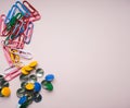 Multi-colored paper clips and buttons are scattered on a pink background. View from above. Concept back to school Royalty Free Stock Photo