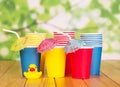 Multi-colored paper cups, straws on green abstract background. Royalty Free Stock Photo