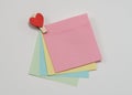 Multi-colored paper notes fastened with a wooden clothespin in heart form on a white background Royalty Free Stock Photo