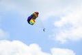 Multi-colored parachute with man soars in the blue sky between white clouds Royalty Free Stock Photo