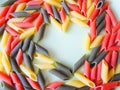 Multi-colored pasta in plates in the form of a heart on a white table. beautiful colored pasta lie in a plate of heart shape, Royalty Free Stock Photo