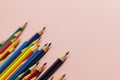 Multi-colored pencils of different lengths on a pink background, located on the left corner, extending into the distance. Royalty Free Stock Photo