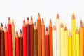 Multi-colored pencils lie on a white table, the red range of colors Royalty Free Stock Photo