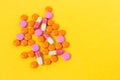 Multi-colored pills on a bright yellow background, top view. Medication for the disease for patients. Dose drugs and vitamins for