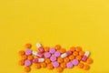 Multi-colored pills on a bright yellow background, top view. Medication for the disease for patients. Dose drugs and vitamins for