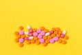 Multi-colored pills on a bright yellow background, top view. Medication for the disease for patients. Drugs and vitamins for healt Royalty Free Stock Photo