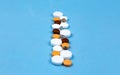 Multi-colored pills and capsules are laid out on a blue background in a row with copy space for text Royalty Free Stock Photo