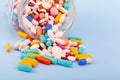 Multi colored pills and capsules spilling out of a large transparent glass jar.Selective focus.ÃÂ¡oncept of treatment, pain relief